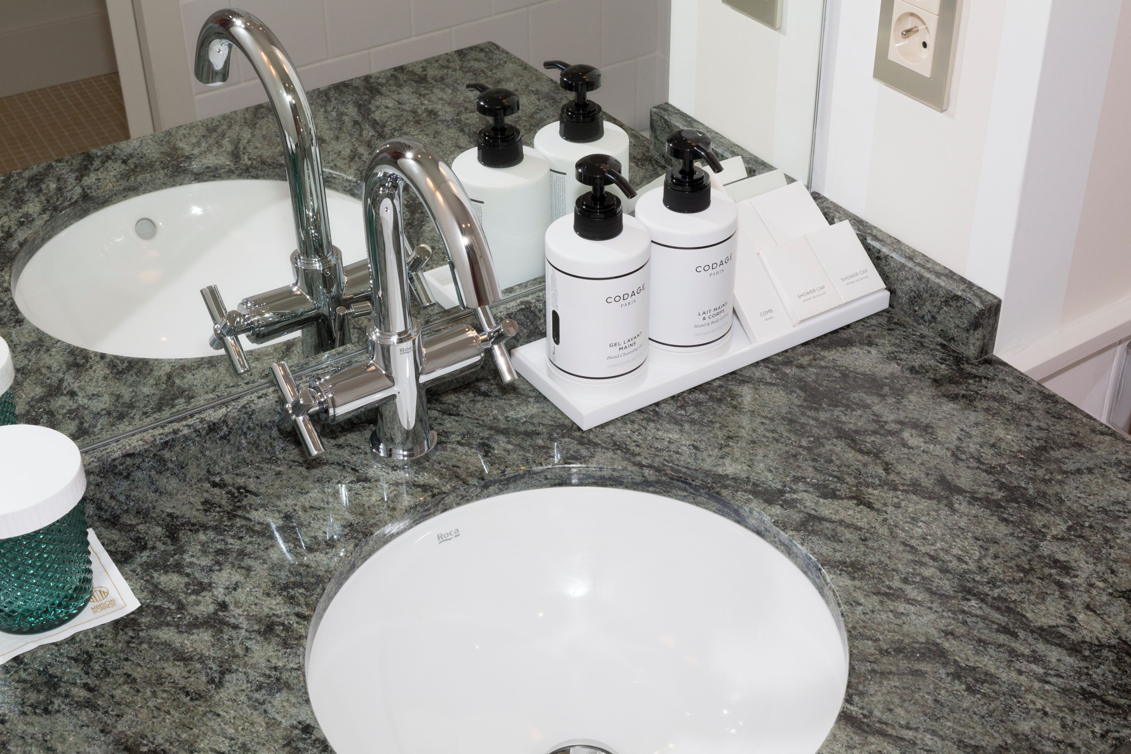 A bathroom with two sinks, a modern faucet, and a soap dispenser set.