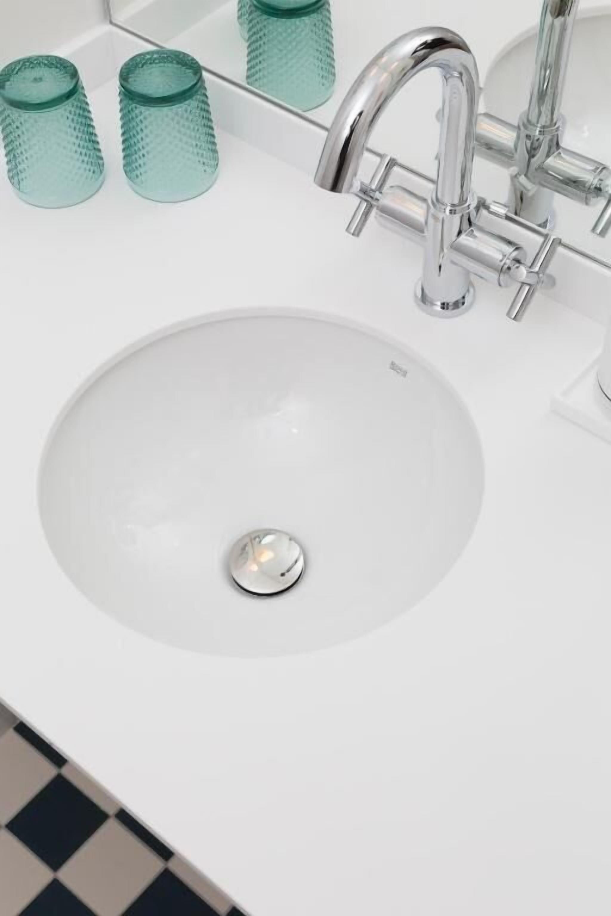 A white sink with a chrome faucet and a drain stopper.
