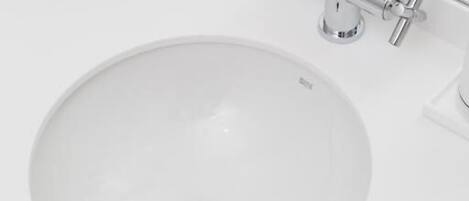 A white sink with a chrome faucet and a drain stopper.