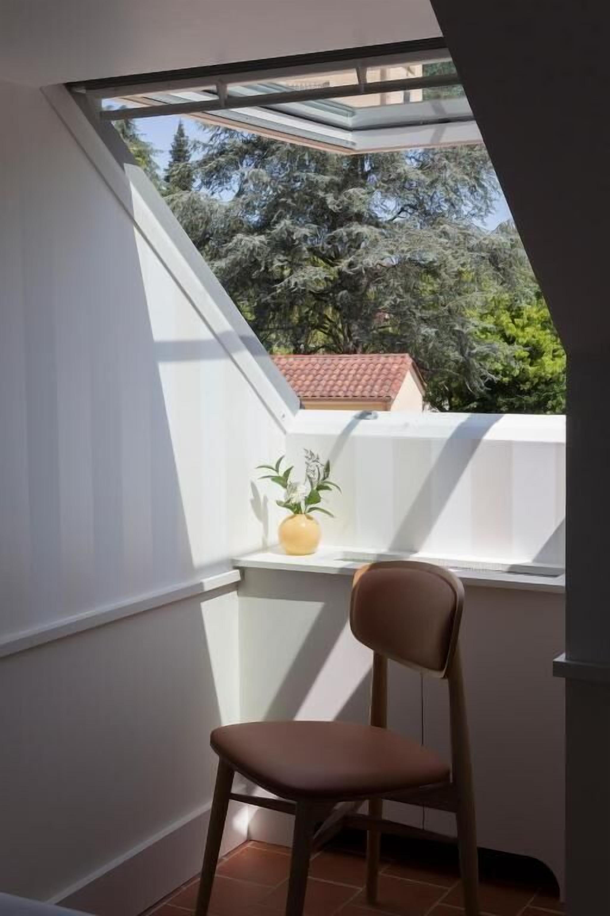 Une pièce dotée d’une lucarne, d’une chaise et d’une plante en pot.