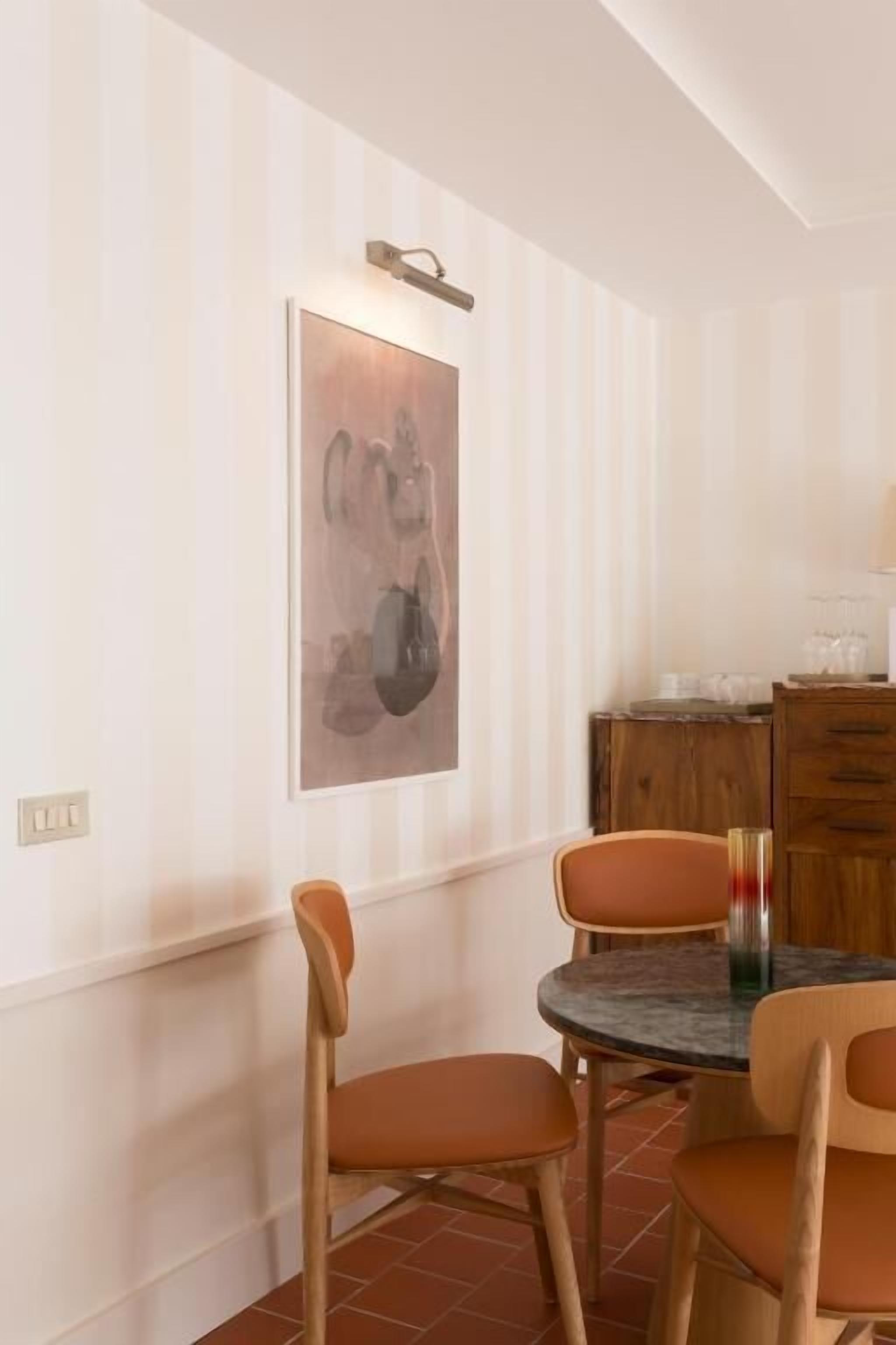 A dining area with striped wallpaper, a table with chairs, and a kitchen area in the background.