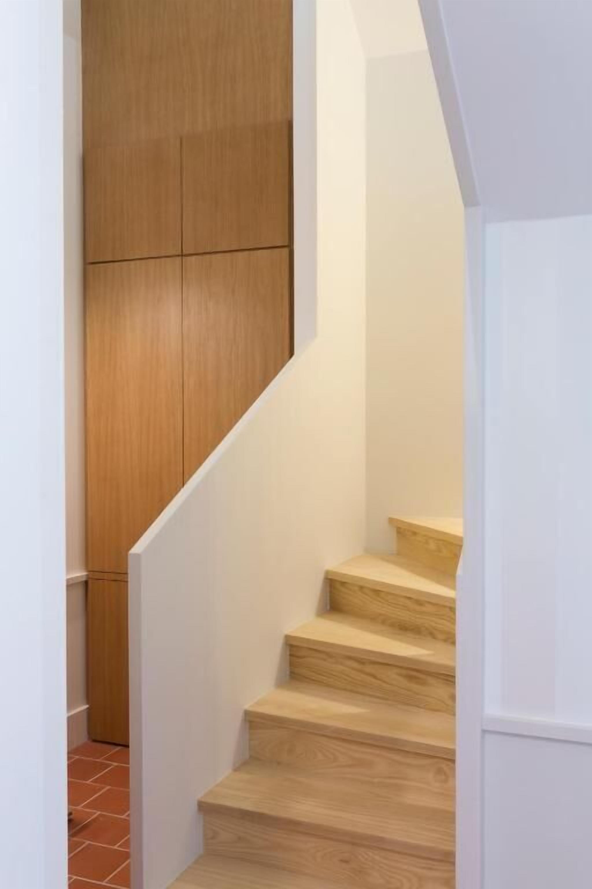 Un escalier en bois, avec des murs blancs et un sol carrelé.