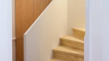 Un escalier en bois, avec des murs blancs et un sol carrelé.