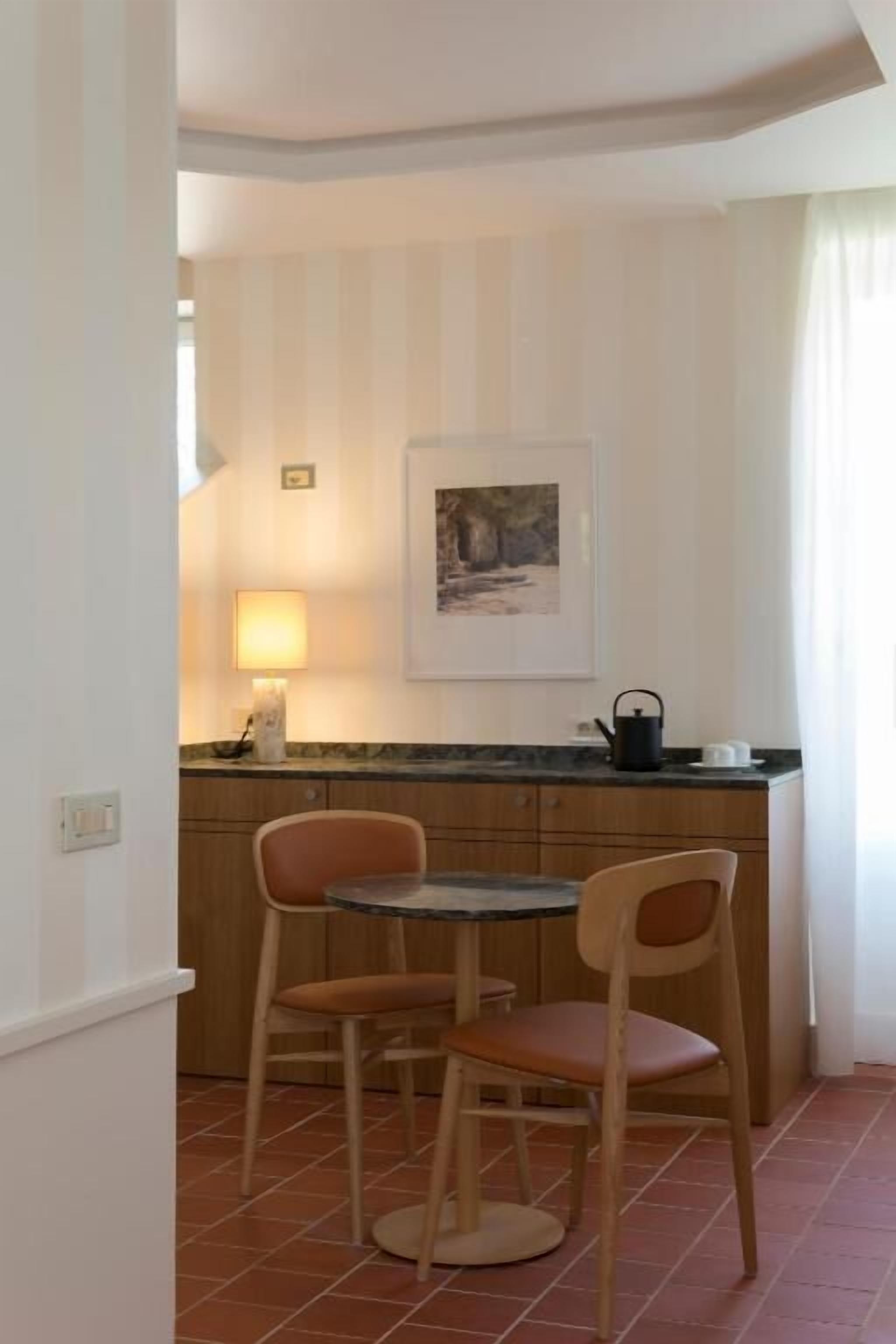 Eine kleine Küche mit Esstisch und Stühlen, einer Arbeitsplatte und einem an der Wand hängenden Bild.