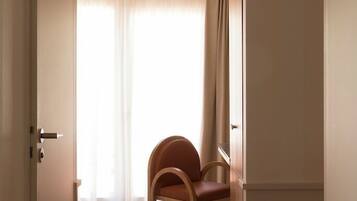 A hallway with a wooden chair, a door, and a window with curtains.