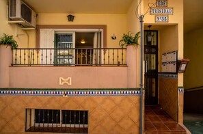 Une entrée d’immeuble avec un balcon, une enseigne indiquant « EDF Trinidad N°35 », et une porte donnant accès à l’intérieur.
