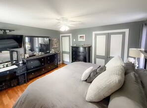 Une chambre à coucher avec un lit, une commode, un miroir et un ventilateur de plafond.