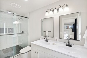 A modern bathroom with a glass-enclosed shower, a white sink with a mirror above it, and a large mirror on the wall. - Pikes Peak View  5 Private Acres Game Room (Colorado Springs)