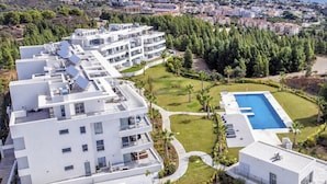 Un hotel moderno con varios pisos, piscina y zonas verdes circundantes.