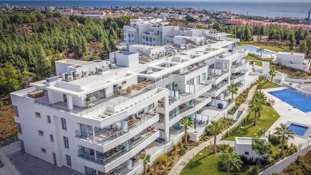 Un edificio moderno de varios pisos con balcones, piscina y vista al mar.
