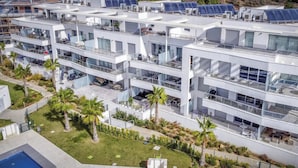 Un hotel moderno de varios pisos con balcones, paneles solares y zona de piscina.