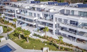Ein modernes Mehrstöckiges Hotel mit Balkonen, Solaranlagen und einem Poolbereich.