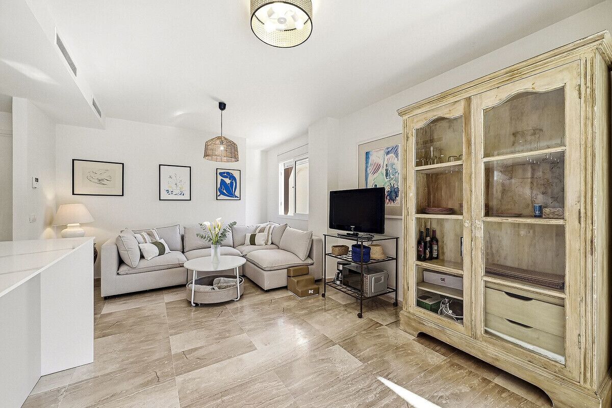 A modern living room with a sofa, coffee table, TV, and a cabinet.