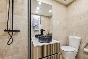 A modern bathroom with a toilet, a sink with a marble basin, and a shower area. - Apartment Alicate Playa by the sea (Marbella)