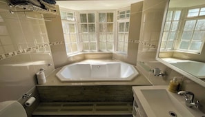 A modern bathroom with a large bathtub, a separate shower area, and a window with frosted glass. - Room-storms River Room, 400 Mbps Interne (Cape Town)