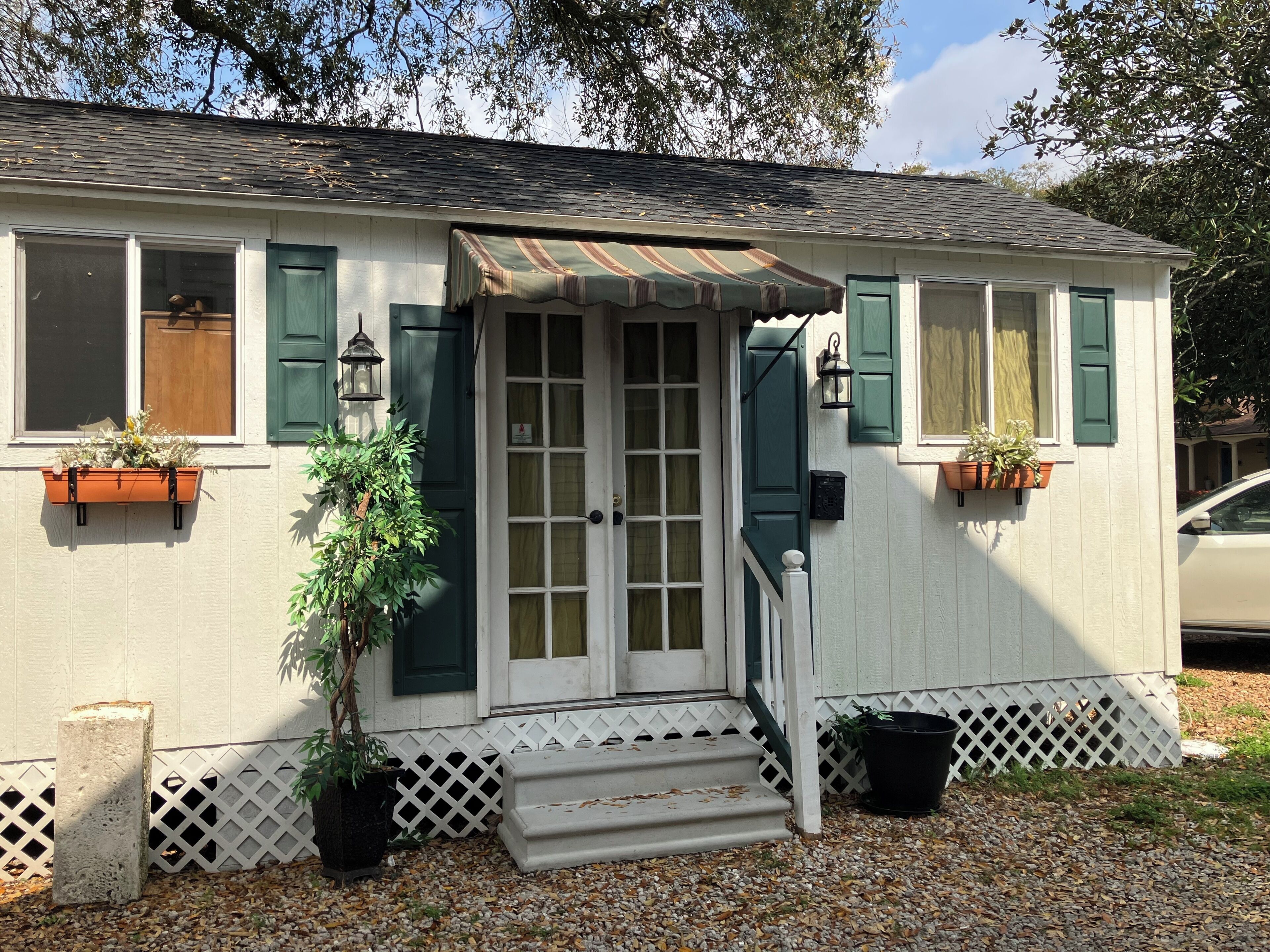 A house with a front door, windows, and a small porch.. Comfy quaint 1-bedroom cottage with serene pond area in charming Abbeville