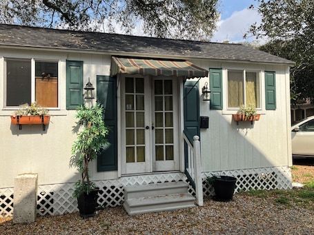 A house with a front door, windows, and a small porch.. Comfy quaint 1-bedroom cottage with serene pond area in charming Abbeville