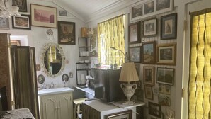 A room with a bed, a desk, a mirror, a lamp, and a wall adorned with framed pictures. - Comfy quaint 1-bedroom cottage with serene pond area in charming Abbeville (Abbeville)
