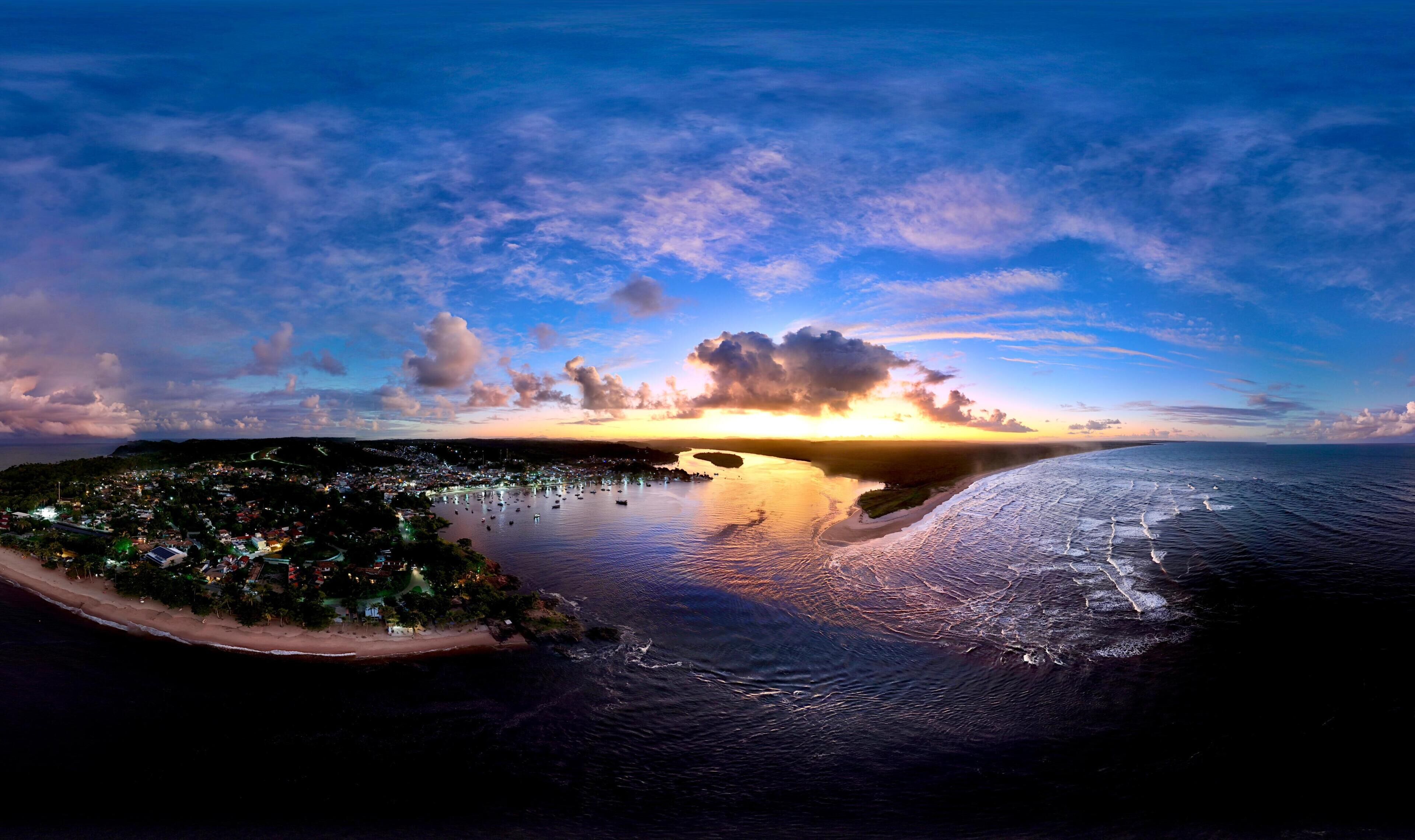 Un pueblo costero con playa, barcos y un atardecer.