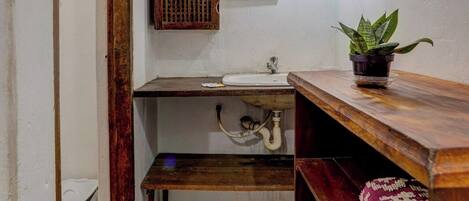 A bathroom with a wooden vanity, a sink, a mirror, a potted plant, and a toilet.