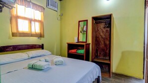 Una habitación de hotel con cama, espejo, estante con toallas y armario de madera.