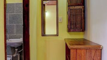 Un couloir étroit avec une armoire en bois, un miroir et un petit lavabo.