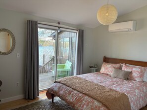 Un dormitorio con cama, mesita de noche, espejo y vista a una terraza.