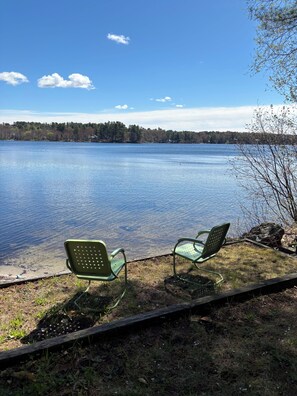 A lakeside view with two green metal chairs facing the water, surrounded by grass and a wooden path. - Cozy, Tranquil Lakefront Retreat (Windham)