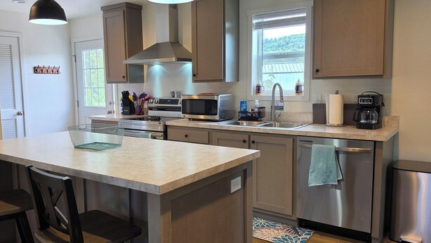 A modern kitchen with a central island, stainless steel appliances, and a window providing natural light. - Beautiful 3-bedroom home in rural Mossyrock.  Close to recreational activities. (Mossyrock)