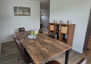 A dining area with a wooden table, chairs, a vase with flowers, and a cabinet with decorative items.