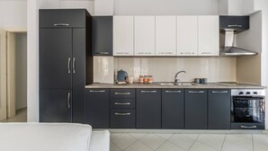 Une cuisine moderne avec des meubles de couleur sombre, un plan de travail blanc, une cuisinière et un évier.