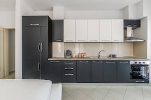 Een moderne keuken met donkere kastjes, een wit aanrecht, een fornuis en een spoelbak.
