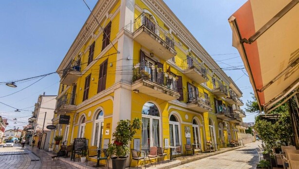 Un immeuble jaune doté de nombreux balcons, avec un café au rez-de-chaussée et donnant sur la rue.