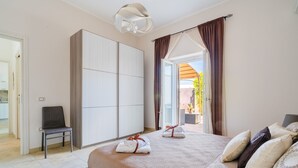 A hotel room with a bed, a chair, a wardrobe, and a view of the outdoors. - Holiday Home 'Marcella' with Private Terrace, Private Garden and Air Conditioning (Torre Lapillo)