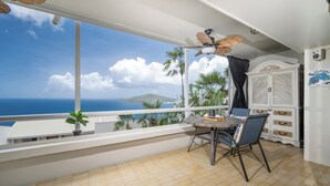 A balcony with a table and chairs, a ceiling fan, and a view of the ocean. - Brand New Centrally Located  2BD/1BA Ocean View (St. Thomas)