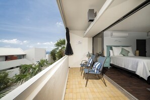 Een balkon met een bed, een stoel en een kleine tafel.