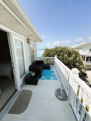 A balcony with a black sofa, a blue patterned rug, and a white railing. - Fully furnished 3BR / 2.5BA townhouse available for monthly stays. (Tybee Island)