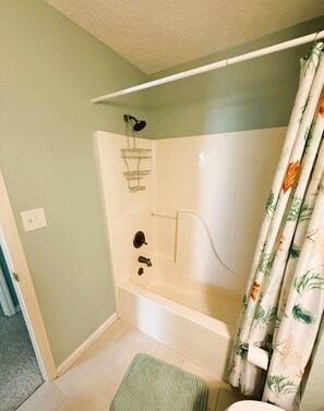 A bathroom with a bathtub, shower, and a green rug. - Fully furnished 3BR / 2.5BA townhouse available for monthly stays. (Tybee Island)