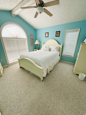 A bedroom with a bed, a ceiling fan, a window with blinds, a dresser, and a nightstand with a lamp. - Fully furnished 3BR / 2.5BA townhouse available for monthly stays. (Tybee Island)