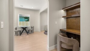 A modern room with a wooden desk, a whiteboard, and a view of a pool. - The O'Four Collection - The Noir (Houston)