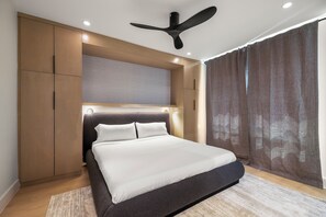 Ein modernes Schlafzimmer mit Bett, Einbauschrank, Deckenventilator und großem Fenster mit Vorhängen.