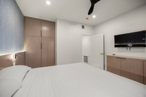 Una habitación de hotel con cama, armario, televisor y ventilador de techo.