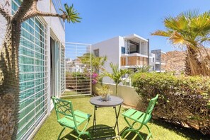 Ein modernes Gebäude mit Balkon, grünen Stühlen, einem kleinen Tisch und einem Blumentopf.
