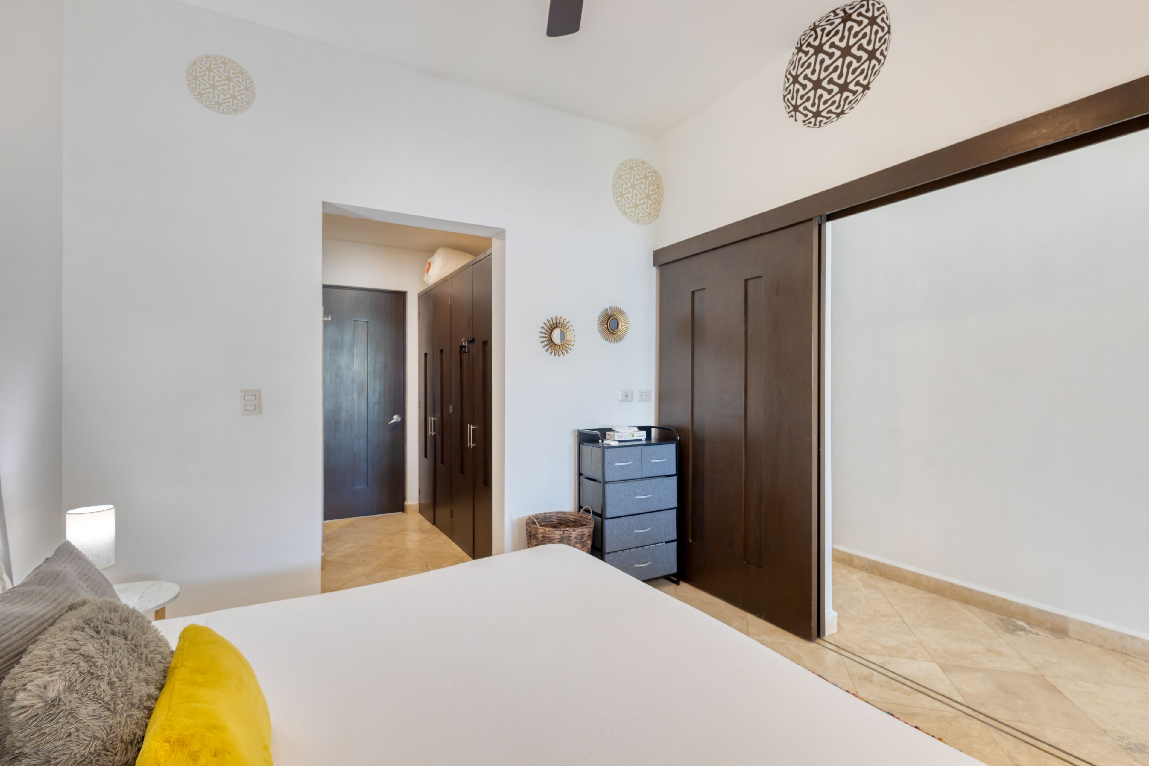 Un dormitorio con cama, armario y escritorio con lámpara.