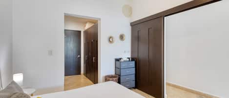 A bedroom with a bed, a wardrobe, and a desk with a lamp.