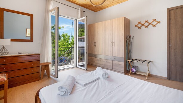 A bedroom with a bed, wooden wardrobe, a mirror, and a balcony with a view. - Apartment 'Anna's House B' with Mountain View, Wi-Fi and Air Conditioning (Chortata)