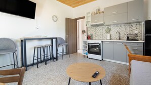 A modern kitchen with grey cabinets, a built-in oven, and a dining area with stools. - Apartment 'Anna's House B' with Mountain View, Wi-Fi and Air Conditioning (Chortata)