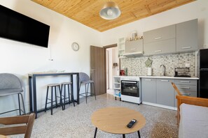 A modern kitchen with grey cabinets, a built-in oven, and a dining area with stools. - Apartment 'Anna's House B' with Mountain View, Wi-Fi and Air Conditioning (Chortata)