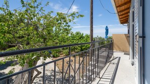 A balcony with a metal railing, a view of trees, and a building with a beige wall. - Apartment 'Anna's House B' with Mountain View, Wi-Fi and Air Conditioning (Chortata)