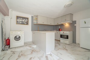 Eine kleine Küche mit Waschmaschine, Backofen und einer Kochinsel.
